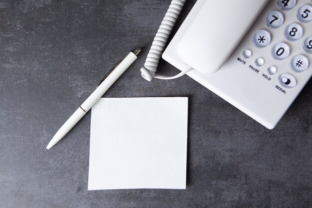 Ein Blatt Papier, ein Stift und ein Telefon zu Hause auf dem Tisch