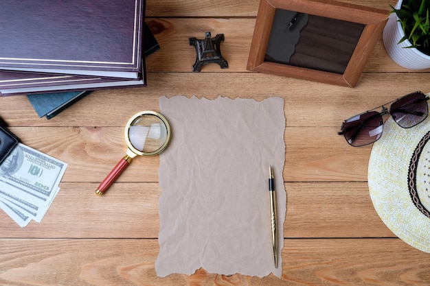 Ein Blatt Papier, ein Stift und eine Lupe auf einem Holztisch