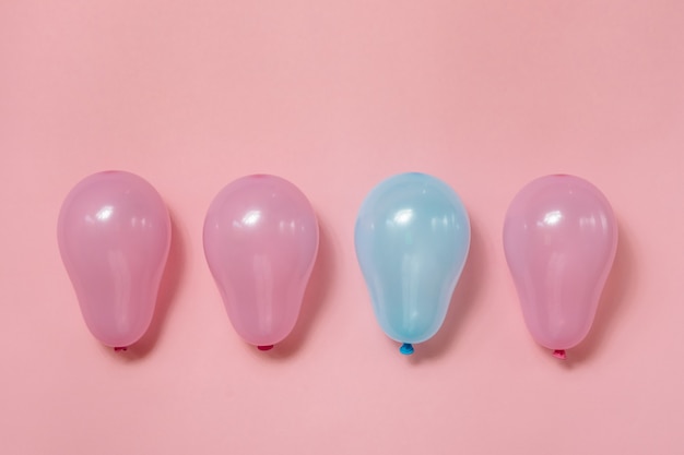 Ein blauer Ballon unter vielen rosa Luftballons auf rosa Hintergrund. Konzept der Gleichstellung der Geschlechter.