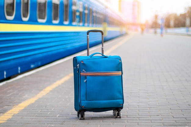 Ein blauer Handgepäckkoffer mit Rädern und einem Metallgriff steht am Rand der Station