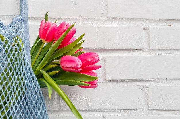 Foto ein blauer stuhl mit rosa tulpen davor.