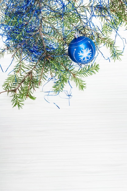 Ein blauer Weihnachtsball und ein Baumast auf leerem Papier