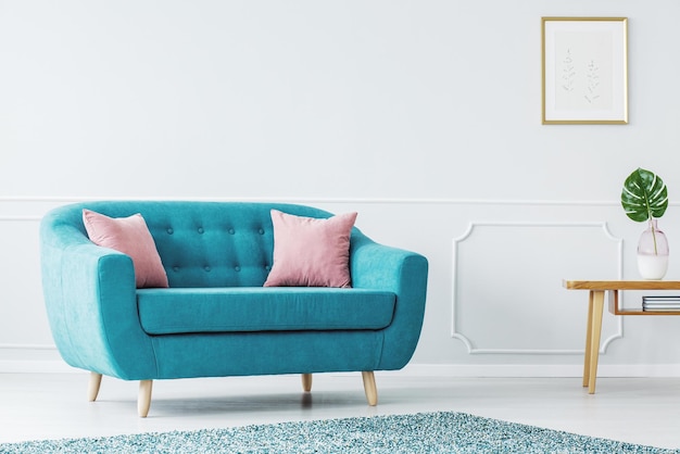 Ein blaues Sofa in einem Wohnzimmer mit einem rosa Kissen auf der Couch.