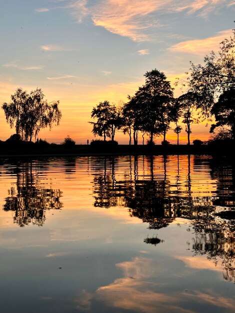 Ein Blick auf Bäume, die sich im Wasser widerspiegeln, und auf den Sonnenuntergang