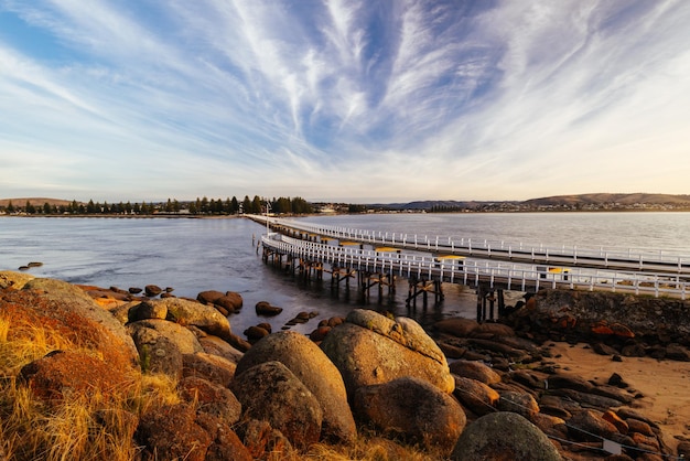 Ein Blick auf den berühmten Damm, der zum Granite Island Recreation Park führt, bei Sonnenaufgang in Victor Harbor an einem sonnigen Herbsttag in Südaustralien Australien