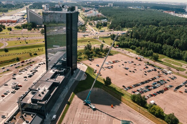 Ein Blick aus der Höhe des höchsten Autokrans, der auf dem Parkplatz in der Nähe des Glasgebäudes der Stadt offen und arbeitsbereit ist. Der höchste Mobilkran wird auf der Baustelle eingesetzt.