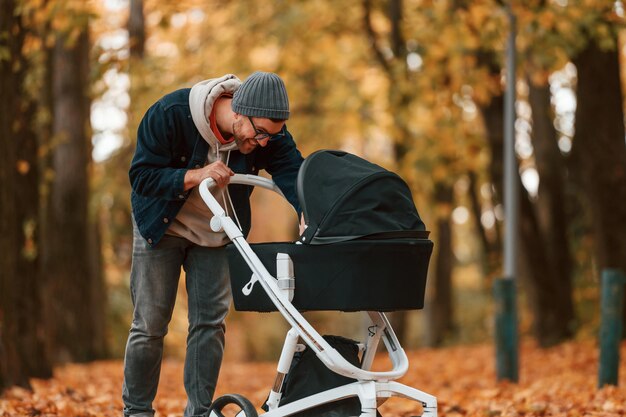 Foto ein blick in den kinderwagen. der mann macht einen spaziergang im herbstpark