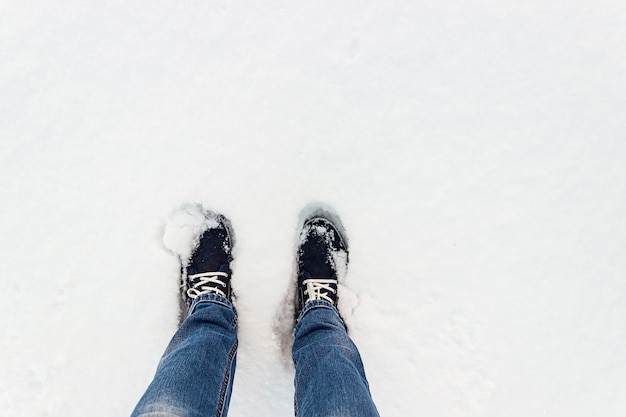 Ein Blick von oben auf blaue Turnschuhe im Schnee.