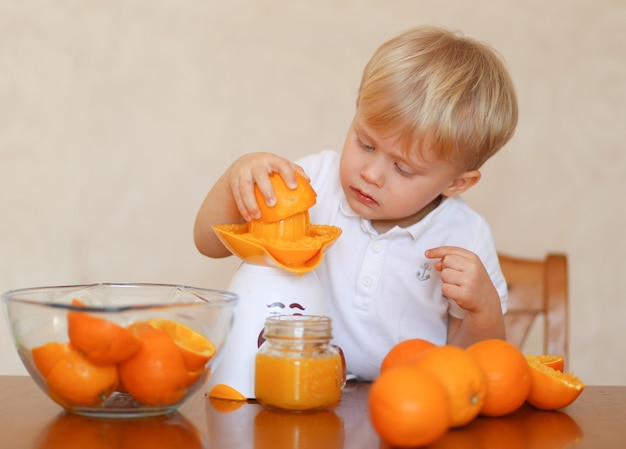 Ein blondes hübsches kind macht frischen orangensaft