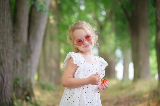 Ein blondes Mädchen in einem Kleid geht an einem Sommertag im Park spazieren