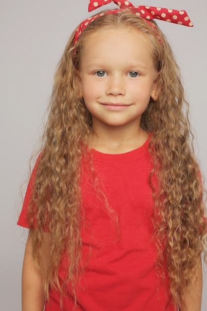 ein blondes Mädchen in einem roten T-Shirt und Jeans mit langen welligen Haaren