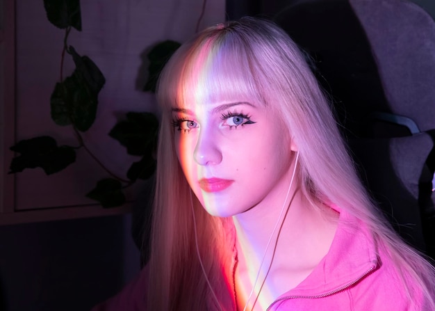 Foto ein blondes mädchen in ihrem zimmer sitzt mit kopfhörern in einer regenbogen-licht-close-up-aufnahme ihres gesichts auf einem stuhl