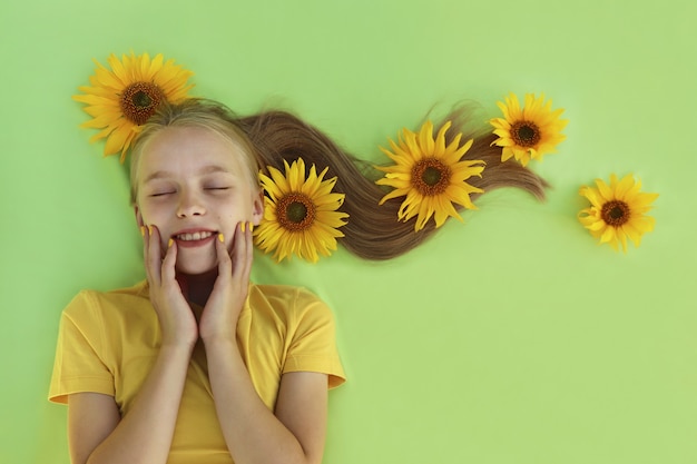 Ein blondes Mädchen mit einer babygelben Maniküre und Sonnenblumen im Haar