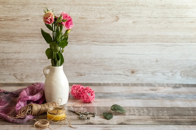 Ein Blumenstrauß in einer weißen Vase schert ein Seil und eine Kerze auf einem Postkartenfoto aus Holzhintergrund