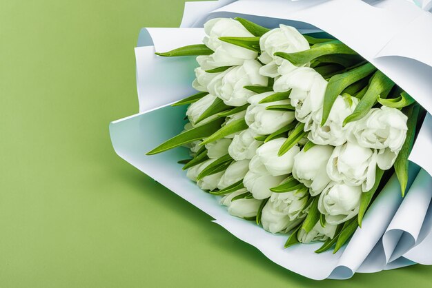 Ein Blumenstrauß weißer Tulpen auf einem pastellgrünen Hintergrund Blütenblumen festliches Konzept