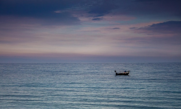 Ein Boot an einem mediterranen Strand des Ionischen Meeres bei Sonnenuntergang Bova Marina Calabria Italien