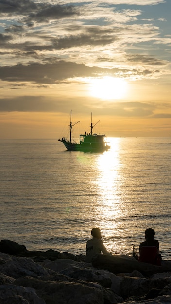 Ein Boot segelt im Wasser, hinter dem die Sonne untergeht