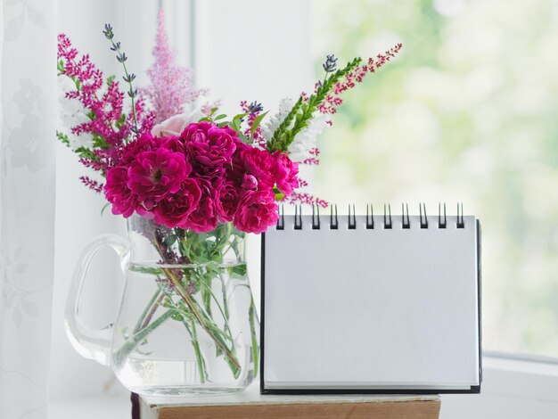 Ein Bouquet von leuchtenden Blumen und eine leere Notizbogenseite