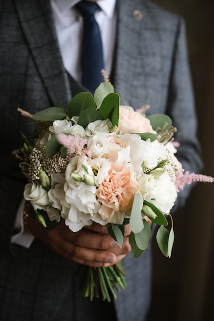 Ein Bräutigam, der schöne Hochzeitsblumenstraußnahaufnahme hält