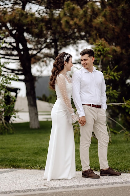 Ein Brautpaar steht auf einem Feld und der Bräutigam trägt ein weißes Kleid mit Spitzenärmeln.