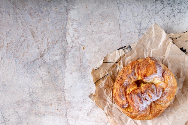 Ein Brötchen liegt auf Vintage-Papier auf einem beigen Hintergrundkopienraum