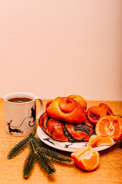 Ein Brötchen mit Mohn auf einem Tisch mit Mandarinen auf einem weißen Teller mit Hirsch neben einer Tasse