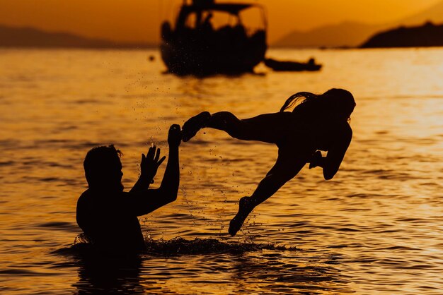 Ein Bruder und eine Schwester genießen bei Sonnenuntergang verspielte Momente im Meer und verkörpern damit die Liebe ihrer Geschwister