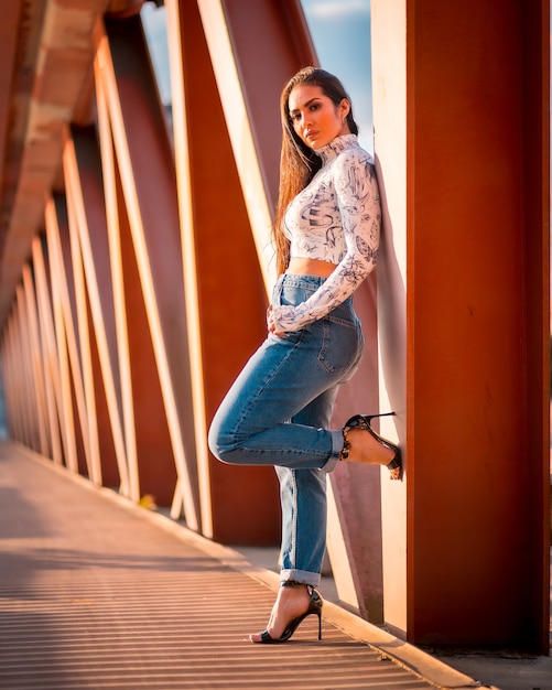 Ein brünettes lateinamerikanisches Mädchen in den Jeans in der Stadt bei Sonnenuntergang