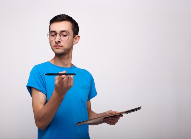 Ein brütender junger Mann mit Brille mit einem Stift auf einem Weiß.