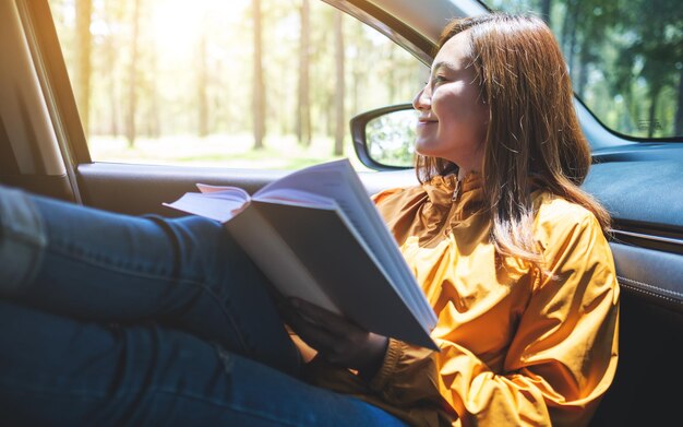 Ein Buch der jungen asiatischen Frau, während sie mit dem Auto fährt