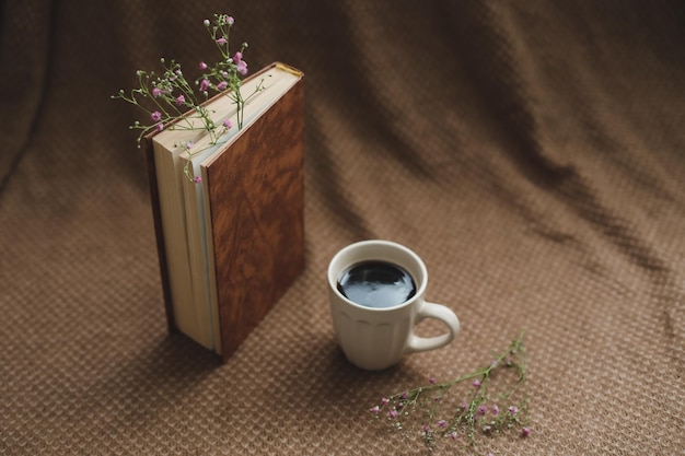 Ein Buch mit Blumen und Tasse Kaffee auf Draufsicht des dunklen Hintergrundes