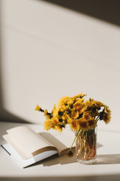 ein Buch und ein Haufen gelber Löwenzahn