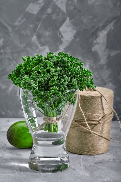 Ein bündel frische, lockige petersilie in einer vase mit wasser. back layout mit umweltfreundlicher verpackung