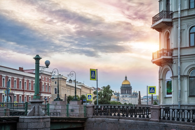 Ein bunter Morgenhimmel über der Kuppel der St. Isaaks-Kathedrale und den Laternen der Krasnoflotsky-Brücke über die Moika an einem Sommermorgen in St. Petersburg