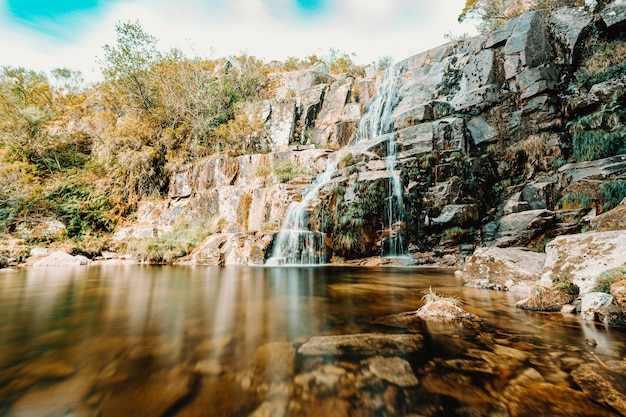 Ein bunter Wasserfall mitten im Wald während eines sonnigen Tages