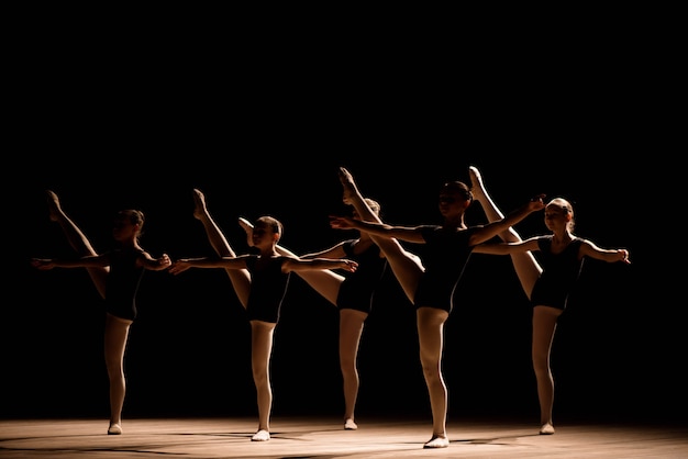 Ein choreografierter Tanz einer Gruppe anmutiger hübscher junger Ballerinas, die auf der Bühne einer klassischen Ballettschule üben