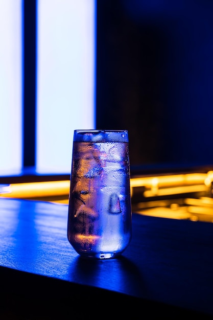 Ein Cocktail an der Bar, aufgenommen im Neonlicht. Lange Verschlusszeit, dunkles Low-Key-Foto