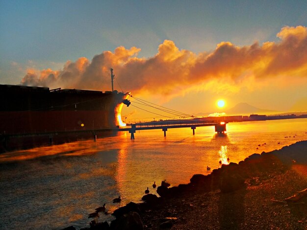 Foto ein containerschiff, das bei sonnenuntergang im meer verankert ist, aus tiefer sicht