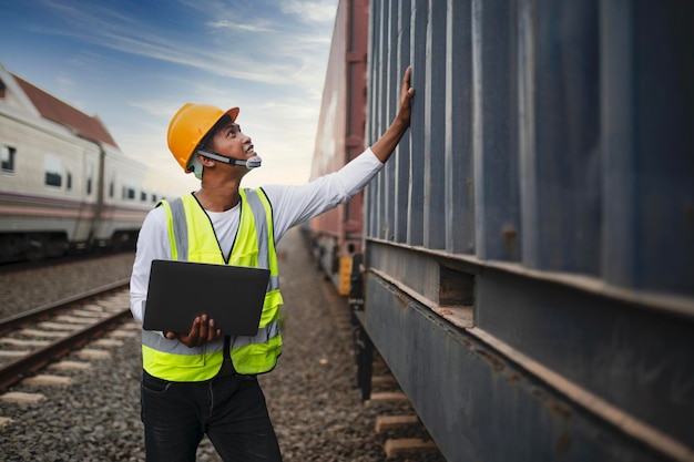 Ein Containerzug, der durch ein Industriegebiet fährt, wird von einem Maschinenbauer überprüft.