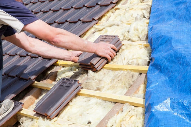 Ein dachdecker, der fliese auf das dach legt