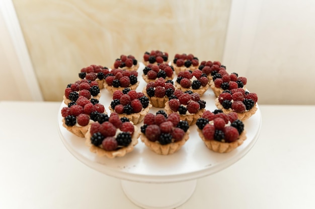 Ein Dessertteller mit kleinen Törtchen mit Himbeeren darauf.