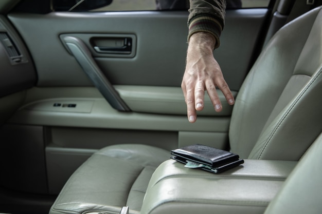 Ein Dieb mit einer Waffe stiehlt eine Brieftasche aus einem Auto