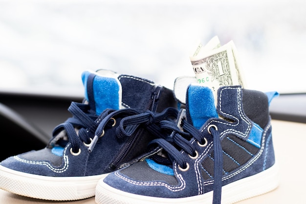 ein dollar in blauen schuhen für kinder im innenraum eines modernen autos geld als geschenk