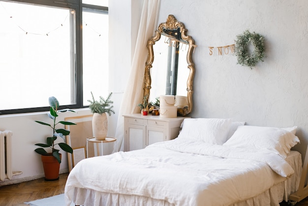 Ein Doppelbett mit weißer Bettwäsche und Kissen im Schlafzimmer, das für Weihnachten und Silvester dekoriert ist