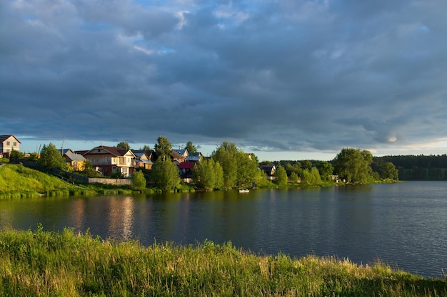 Ein Dorf am Flussufer mit hellgrünem Gras und einem wunderschönen Himmel