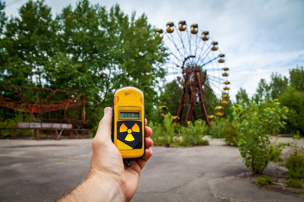Ein Dosimeter in Händen mit einem Grad an Radioaktivität in einem verlassenen Vergnügungspark