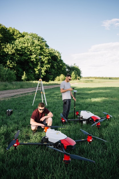 Foto ein drohnenpilot, der seine drohne vor dem flug auf einem feld mit einem bewässerungssystem konfiguriert