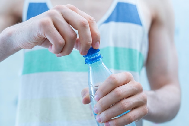 Ein dünner Sportler mit einer Plastikflasche mit reinem Wasser während des Trainings