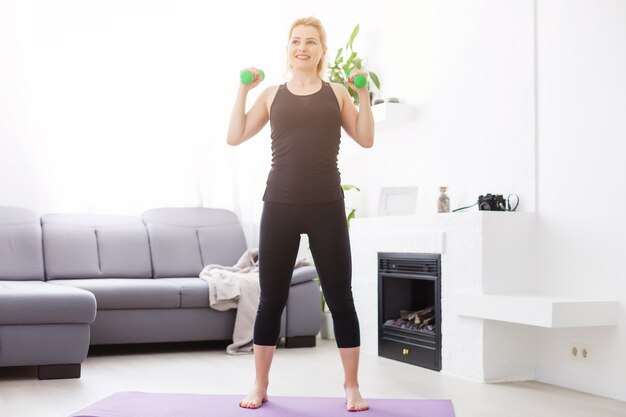 ein dünnes europäisches mädchen, das zu hause auf einer yogamatte dehnübungen macht, lichtstrahlen scheinen aus dem fenster. aufflackern. Quarantäne Sport.