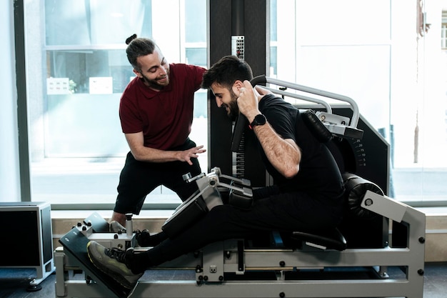 Ein dunkelhaariger Typ, der mit seinem Personal Trainer das Bein trainiert